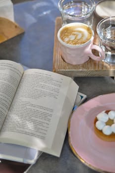 about-us Relaxing setup with coffee, book, and dessert on a sunny table.