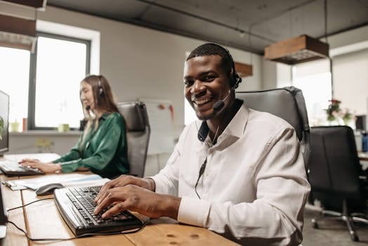 Two professionals in an office wearing headsets, engaging in friendly teamwork.
